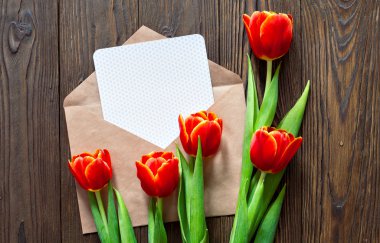 kırmızı lale ve kraft zarf ahşap arka plan üzerinde