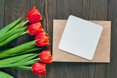 kırmızı lale ve kraft zarf ahşap arka plan üzerinde