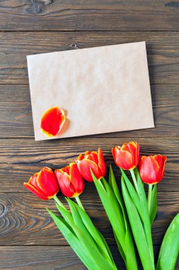kırmızı lale ve kraft zarf ahşap arka plan üzerinde