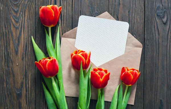 kırmızı lale ve kraft zarf ahşap arka plan üzerinde
