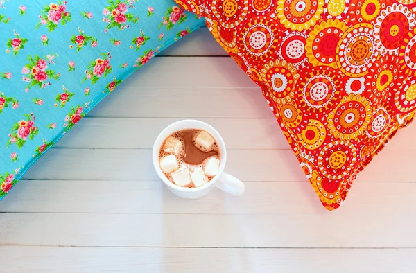 Oreillers confortables colorés et tasse de cacao à la main — Photo