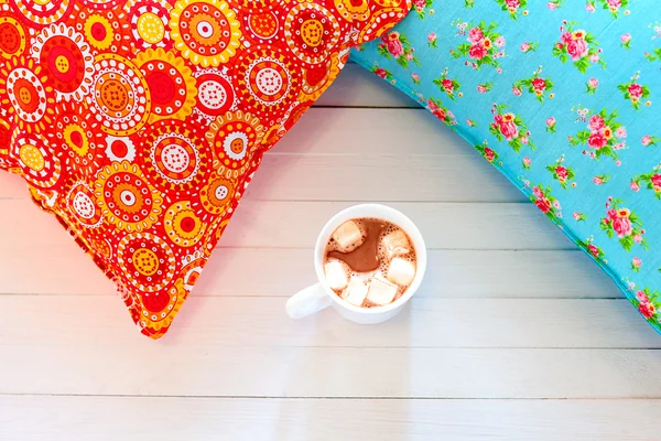 Oreillers confortables colorés et tasse de cacao à la main — Photo