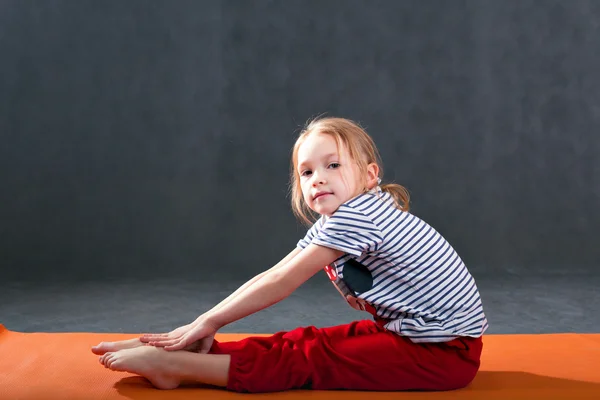 küçük kız bir yoga mat germe için jimnastik egzersizleri yapıyor.