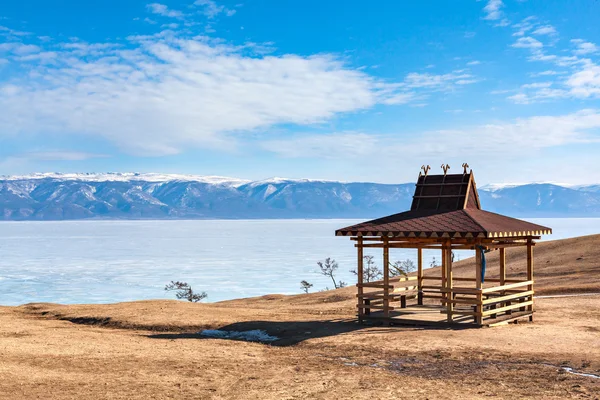 Olkhon adasındaki kış manzarası. Buryat bölgesi, Rusya, Sibirya. Buryat tarzında geleneksel ahşap çardak Baykal Gölü kıyısında, arka planda kış dağlarında..