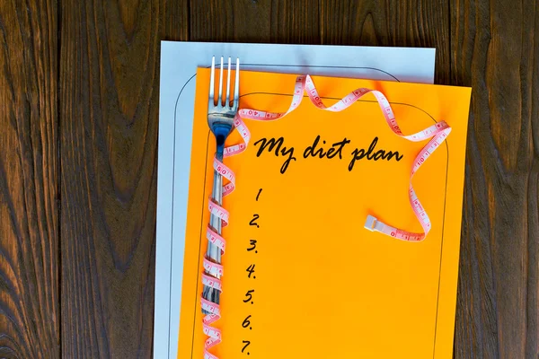 Diet plan on orange and white sheet of paper with a measuring tape. — Stock Photo, Image