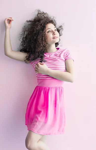 Ein junges Mädchen kaukasischen Aussehens tanzt und träumt von einem hellen Raum an einem Sommertag. welliges lockiges Haar und ein rosa Kleid. Ruhe und sei glücklich. — Stockfoto