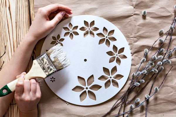 Clase magistral. Reloj hecho a mano. Instrucciones paso a paso para la fabricación de relojes. Manos con pincel base reloj de pintura blanca. Las ramas de sauce contra el telón de fondo de papel kraft —  Fotos de Stock