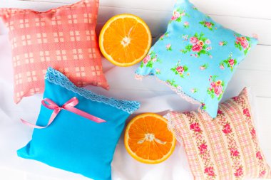 aromaterapi yastıklar, aromatizasyon alanı. Dört küçük dekoratif yastıklar dantel ile mavi ve pembe soluk. El yapımı. İyi bir ruh hali için vitaminler. Beyaz ahşap arka plan ve turuncu yarılar.