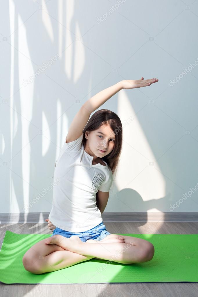 Little girl doing gymnastics on a green yoga mat. childrens