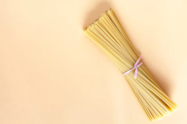 Kopya alanı ile bej arka planda çiğ makarna. İmza için yer. Spagetti.