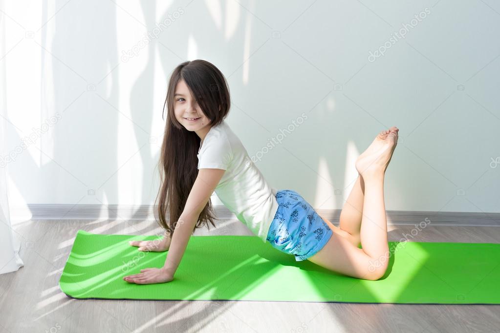 Little girl doing gymnastics on a green yoga mat. childrens