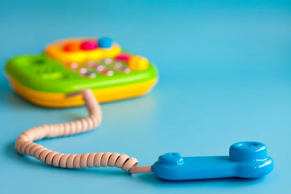 Colorido teléfono móvil de juguete de plástico sobre un fondo azul para niños —  Fotos de Stock