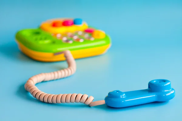 Plastic toy mobile phone on a blue background for children. — Stock Photo, Image