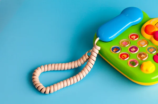 Kolorowa plastikowa zabawka telefon komórkowy na niebieskim tle dla dzieci. — Zdjęcie stockowe