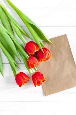 Renkli Lale buketi ve boş tebrik kartı. Beyaz ahşap masa üzerinde Üstten Görünüm