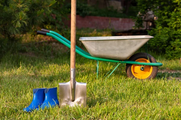 Sekop dan sepatu karet. Peralatan kebun di halaman hijau .. — Stok Foto