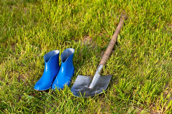 Łopatki i gumowe buty. Narzędzia ogrodowe na zielonym trawniku. — Zdjęcie stockowe