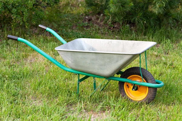 Wheelbarrow. Garden tools on a green lawn.