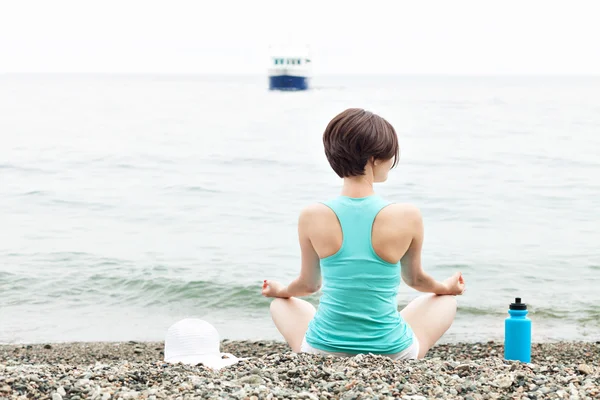 Женщина медитирует на пляже в позе лотоса — стоковое фото