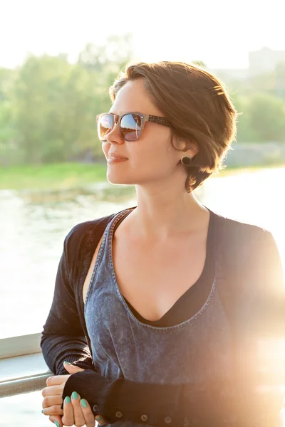 Jeune belle femme en lunettes de soleil au coucher du soleil — Photo