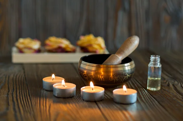 Singing bowl on dark wooden background. Burning candles and oil for aromatherapy and massage.. — Stock Photo, Image