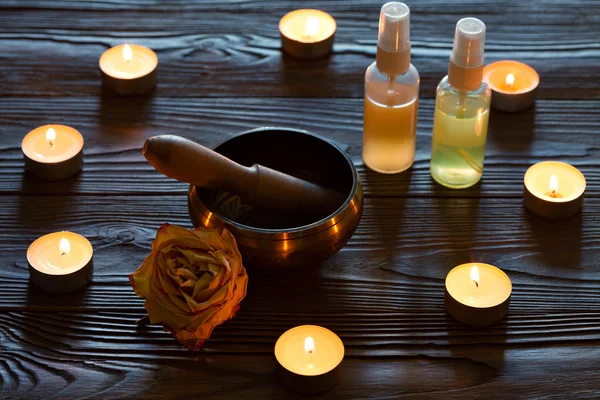 Sjungande skål på mörk trä bakgrund. Brinnande ljus och olja för aromterapi- och massagebehandlingar.. — Stockfoto