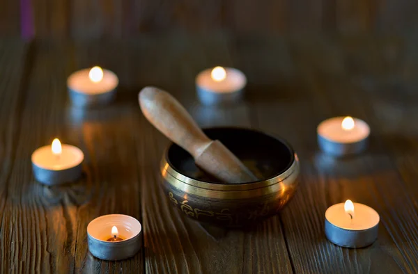 Sjungande skål på mörk trä bakgrund. Brinnande ljus och olja för aromterapi- och massagebehandlingar.. — Stockfoto