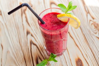 Taze meyve yüzlü berry. Bir bardak portakal ve nane ahşap bir masa üzerinde kırmızı yüzlü. güler yüzlü kavramı