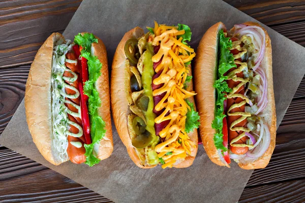 Ketçap, hardal ve salata ahşap arka plan üzerinde çeşitli üç sosisli sandviç