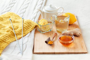 Çiçek papatya, zerdeçal ve bal bir ahşap tahta üzerinde cam bardak bitkisel çay. Bir soğuk içecek ile tedavi. Yatakta halk ilaçları tedavisinde. Hobi örgü.