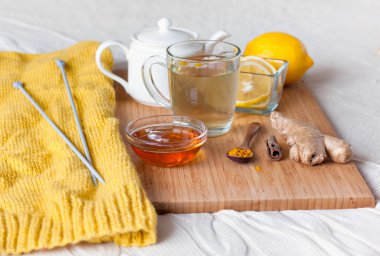 Çiçek papatya, zerdeçal ve bal bir ahşap tahta üzerinde cam bardak bitkisel çay. Bir soğuk içecek ile tedavi. Yatakta halk ilaçları tedavisinde. Hobi örgü.