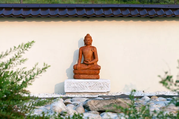 Buddha szobor a kertben, a kövek, egy buddhista templom területén a lenyugvó nap. Datsan Rinpocse Bagsha a Kopasz-hegy Ulan-Ude, Burjátföldön, Oroszország. — Stock Fotó