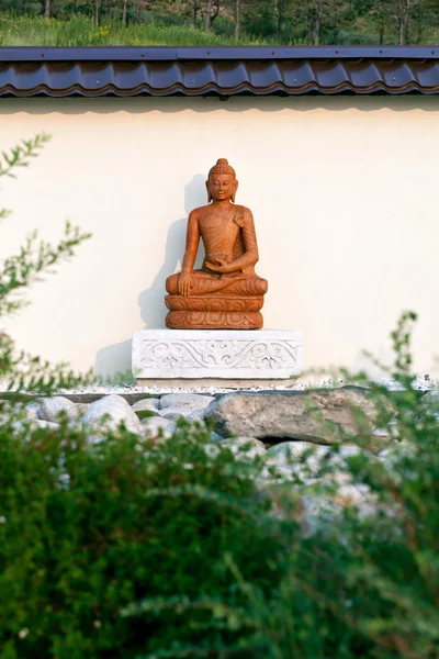 Buddha szobor, a zöld ágak között a kertben a kövek, egy buddhista templom területén. Datsan Rinpocse Bagsha a Kopasz-hegy Ulan-Ude, Burjátföldön, Oroszország. — Stock Fotó