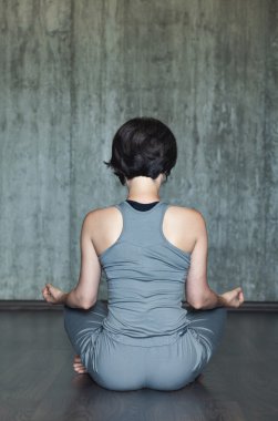 Genç kadın pratik Yoga arka plan gri beton duvar üzerinde. Kentsel arka plan. Tek renkli görüntü.