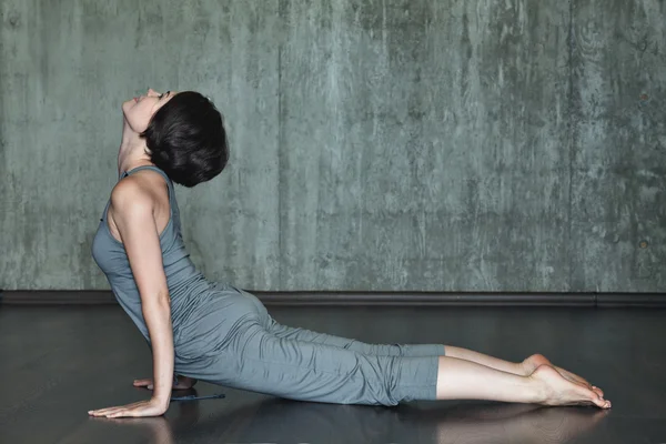 Junge Frau praktiziert Yoga auf einem Hintergrund aus grauer Betonwand. Urbaner Hintergrund. Monochromes Bild. — Stockfoto