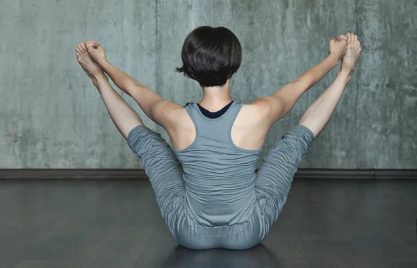 Junge Frau praktiziert Yoga auf einem Hintergrund aus grauer Betonwand. Urbaner Hintergrund. Monochromes Bild. — Stockfoto