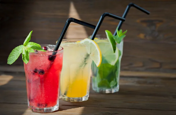 Três limonada refrescante diferente com limão e limão em um fundo de madeira. Bebida de verão . — Fotografia de Stock