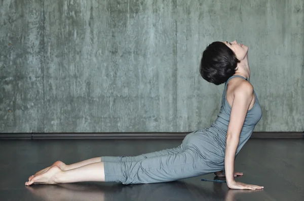 Junge Frau praktiziert Yoga auf einem Hintergrund aus grauer Betonwand. Urbaner Hintergrund. Monochromes Bild. — Stockfoto