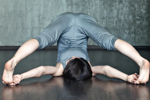 Junge Frau praktiziert Yoga auf einem Hintergrund aus grauer Betonwand. — Stockfoto
