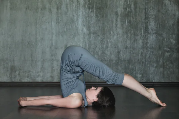 Junge Frau praktiziert Yoga auf einem Hintergrund aus grauer Betonwand. Urbaner Hintergrund. Monochromes Bild. — Stockfoto