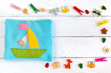 Çocuk oyuncak motor gelişimi için renkli polar yapılmış. Beyaz ahşap arka plan üzerinde plastik boncuk ve heykelcikler ile dolu bir yün bir gemi ile Kese. el yapımı oyuncaklar. Mutlu çocukluk.