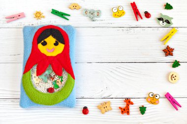 Çocuk oyuncak motor gelişimi için renkli polar yapılmış. Beyaz ahşap arka plan üzerinde plastik boncuk ve heykelcikler ile dolu bir polar ile Çanta matryoshka. el yapımı oyuncaklar. Mutlu çocukluk.
