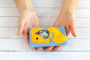 Çocuk oyuncak ellerinde motor becerileri için renkli polar yapılmış kadınlar. Sarı balık ile Çanta beyaz ahşap arka plan üzerinde plastik boncuk ve heykelcikler dolu. el yapımı oyuncaklar