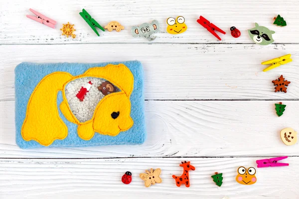 Childrens toys made of colored fleece for motor development. Bag with yellow fish fleece filled with plastic beads and figurines on a white wooden background. handmade toys. Happy childhood.