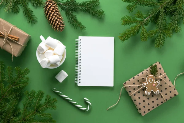 Kerstcompositie. Kerst decoraties, sparren takken en marshmallows op een groene achtergrond. Stockfoto