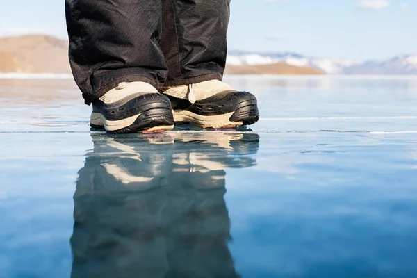 De reflectie in de transparante ijs. Menselijke voet in schoenen op th — Stockfoto