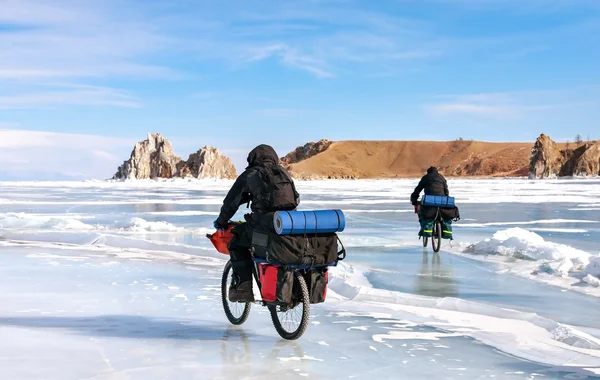 Twee reizigers met rugzakken op fietsen op het ijs van het Baikalmeer. — Stockfoto