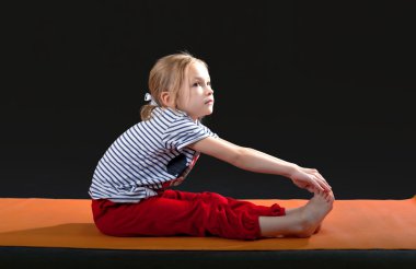Küçük kız 5-7 yıl, mat için yoga egzersizleri yapıyor. Çekme