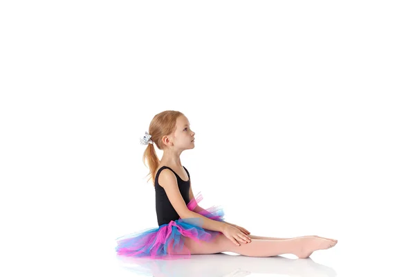 Ittle ballerina sitting on floor on white backgroundn studio pos — Stock Photo, Image