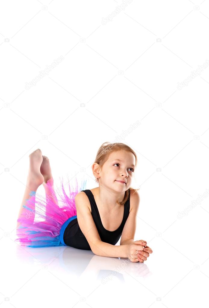 Little ballet dancer lying on the floor face on camera on white 